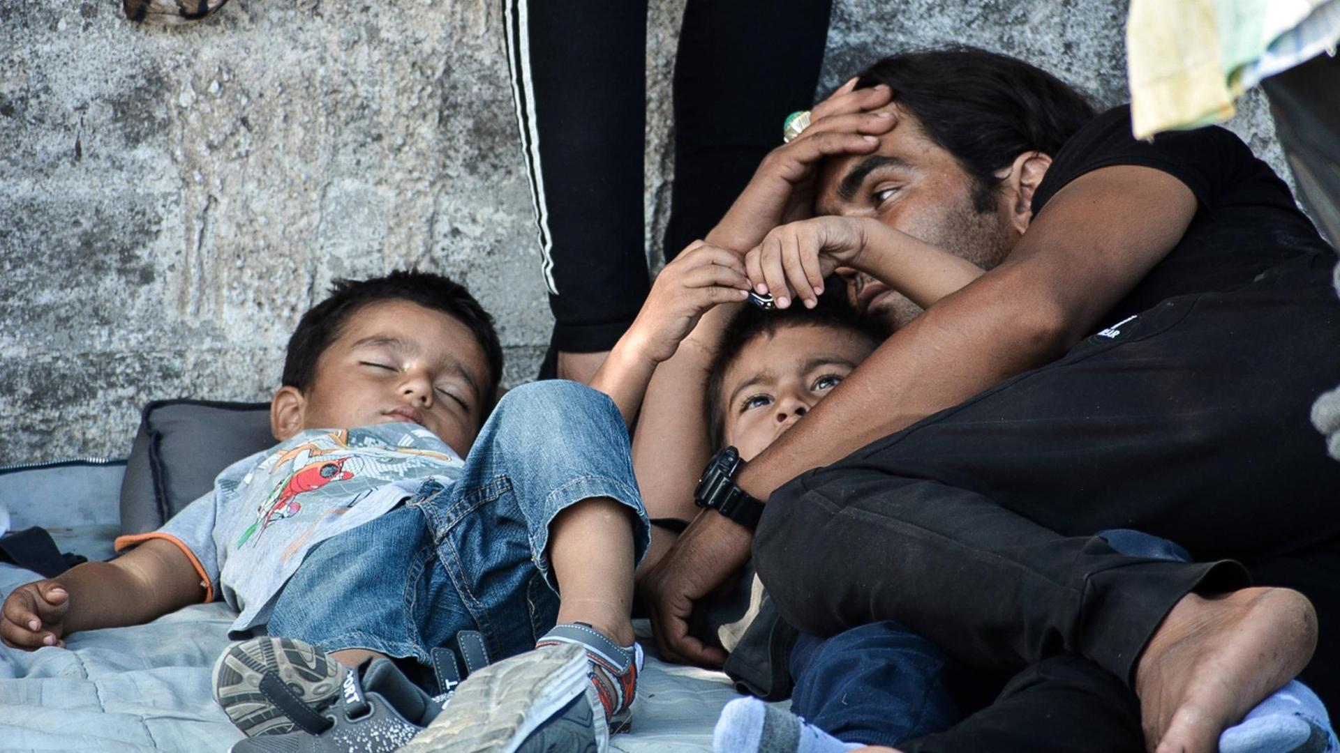 Flüchtlinge auf der griechischen Insel Lesbos: Ein Vater beobachtet seine Kinder, die auf der Straße schlafen. Flüchtlinge auf der griechischen Insel Lesbos: Ein Vater beobachtet seine Kinder, die auf der Straße schlafen.