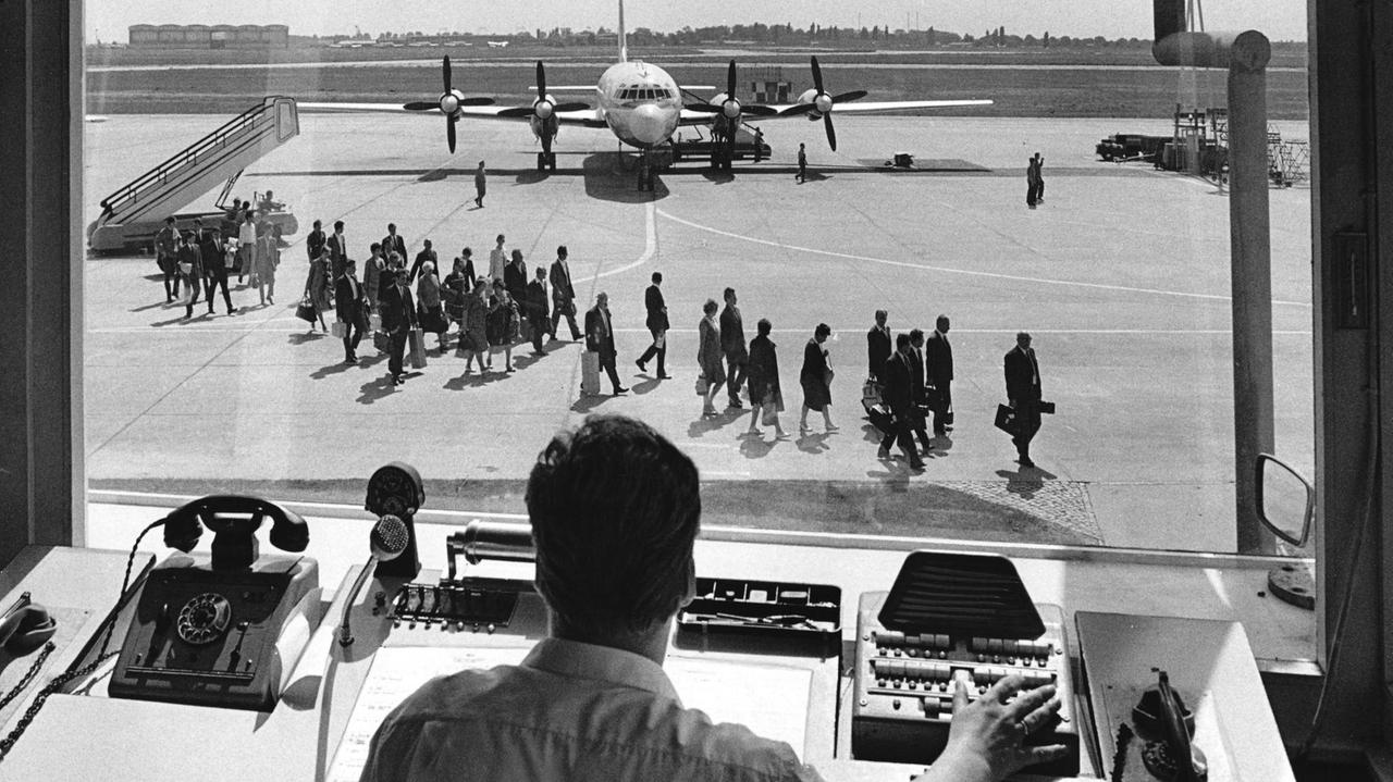 Blick aus der Dispatcherzentrale auf das Vorfeld auf dem Zenralflughafen Berlin-Schönefeld. Vor einem viermotoreigen Propellerflugzeug laufen Passagiere. Blick aus der Dispatcherzentrale auf das Vorfeld auf dem Zenralflughafen Berlin-Schönefeld. Vor einem viermotoreigen Propellerflugzeug laufen Passagiere.