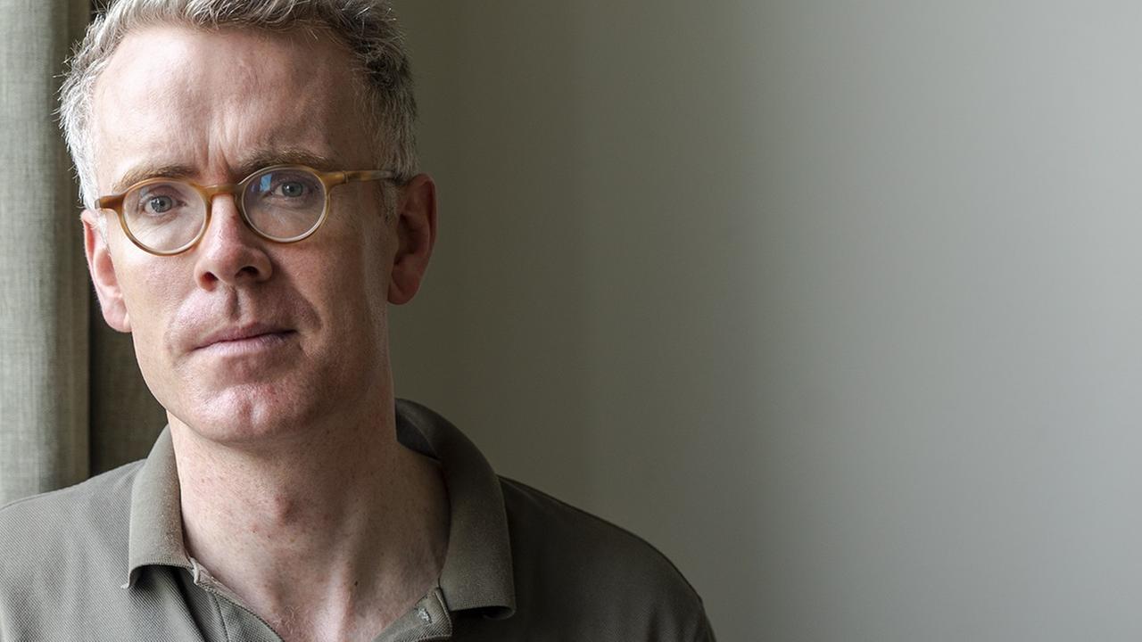Derek Scally trägt Brille, steht am Fenster und schaut in die Kamera. Derek Scally trägt Brille, steht am Fenster und schaut in die Kamera.