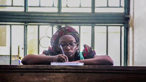 Die prominente Feministin und LGBT-Aktivistin Stella Nyanzi sitzt im Gerichssaal bei Ihnen Anhörung und macht sich Notizen in einen Ringblock.