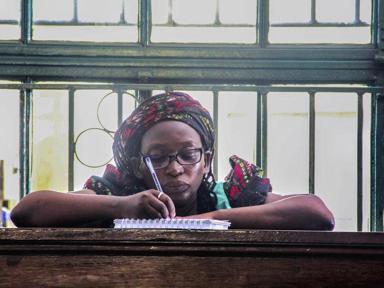 Die prominente Feministin und LGBT-Aktivistin Stella Nyanzi sitzt im Gerichssaal bei Ihnen Anhörung und macht sich Notizen in einen Ringblock.