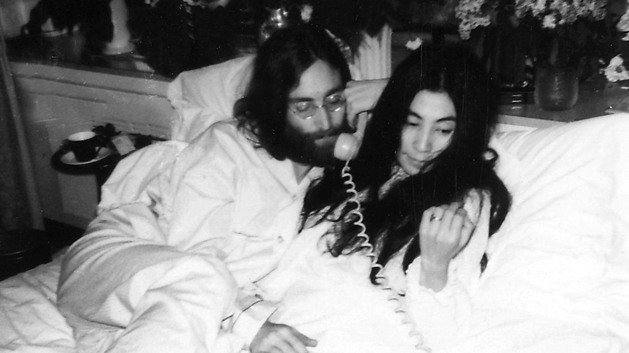 John Lennon und Yoko Ono liegen in einem Hotelbett und telefonieren John Lennon und Yoko Ono liegen in einem Hotelbett und telefonieren