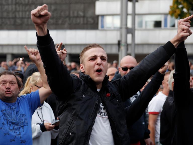 Rechte Demonstranten strecken wutentbrannt ihre Arme in die Höhe.