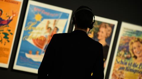 Ein Mann mit Kopfhörer sieht sich im Museum für Kommunikation Berlin bei der Ausstellung "Oh Yeah! Pop Musik in Deutschland" Plakate an.