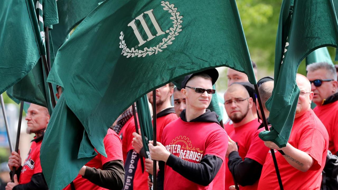 Mehrere Demonstranten in bedruckten roten T-Shirts tragen die grünen Fahnen des "III.Weg" Mehrere Demonstranten in bedruckten roten T-Shirts tragen die grünen Fahnen des "III.Weg"