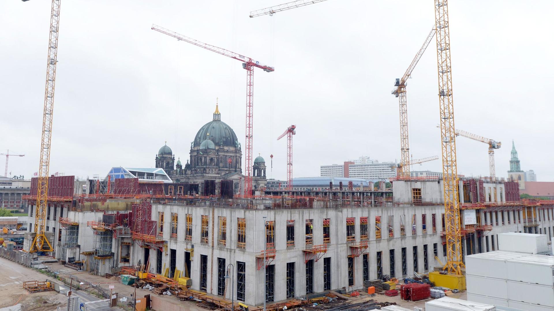 Kräne stehen auf der Baustelle des Berliner Schlosses - Humboldtforum in Berlin. Im Hintergrund ist der Berliner Dom zusehen.
