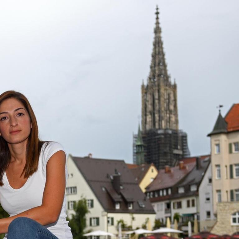 Mesale Tolu sitzt auf einem Geländer vor der Ulmer Altstadt.