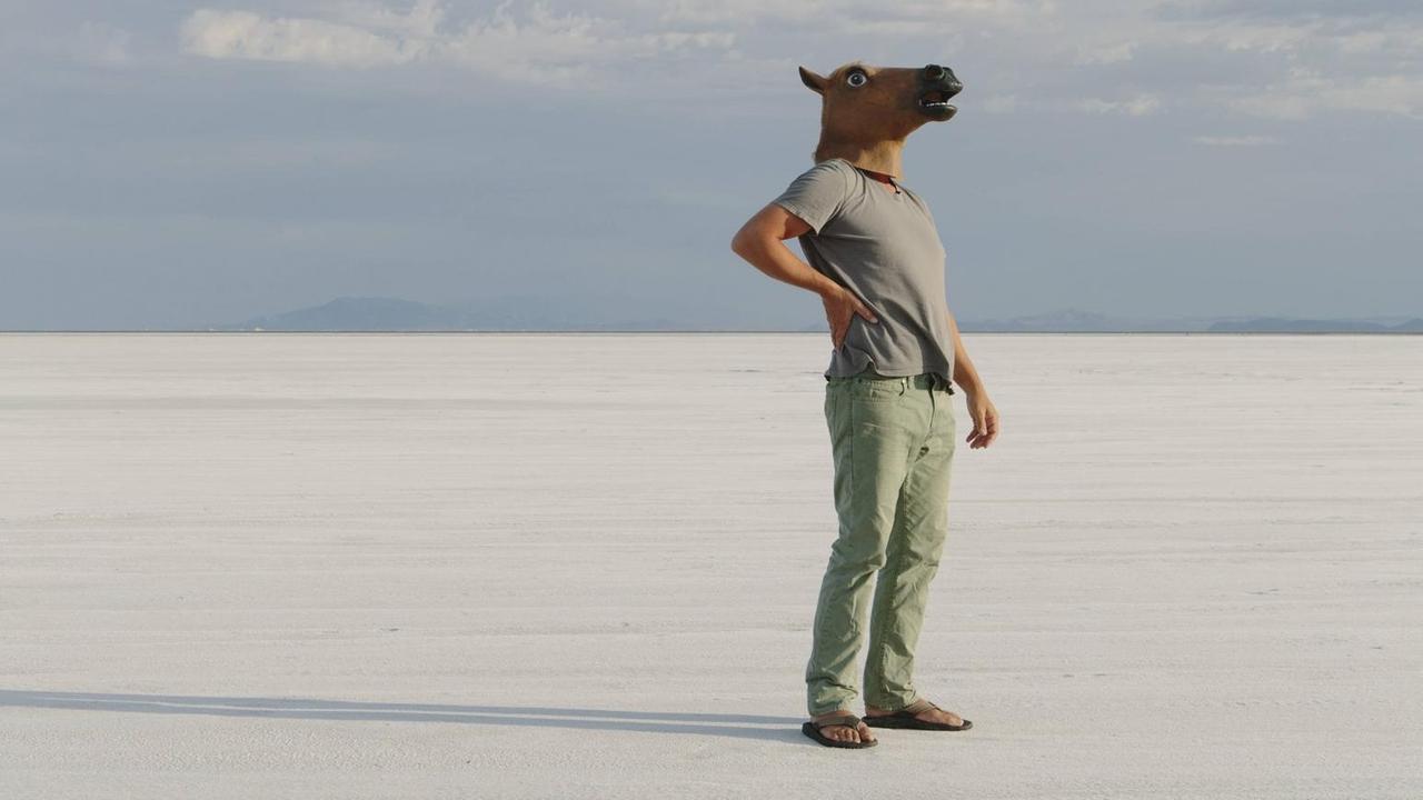 Ein Mann steht mit Pferdemaske in der Großen Salzwüste in im US-Staat Utah. Ein Mann steht mit Pferdemaske in der Großen Salzwüste in im US-Staat Utah.