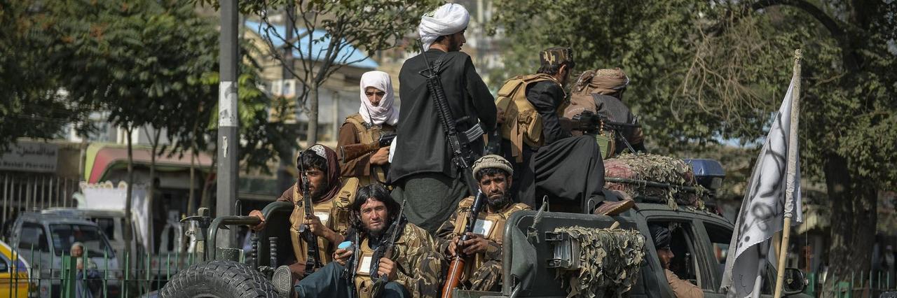 Taliban-Kämpfer patrouillieren in einem Auto entlang einer Straße. Taliban-Kämpfer patrouillieren in einem Auto entlang einer Straße.