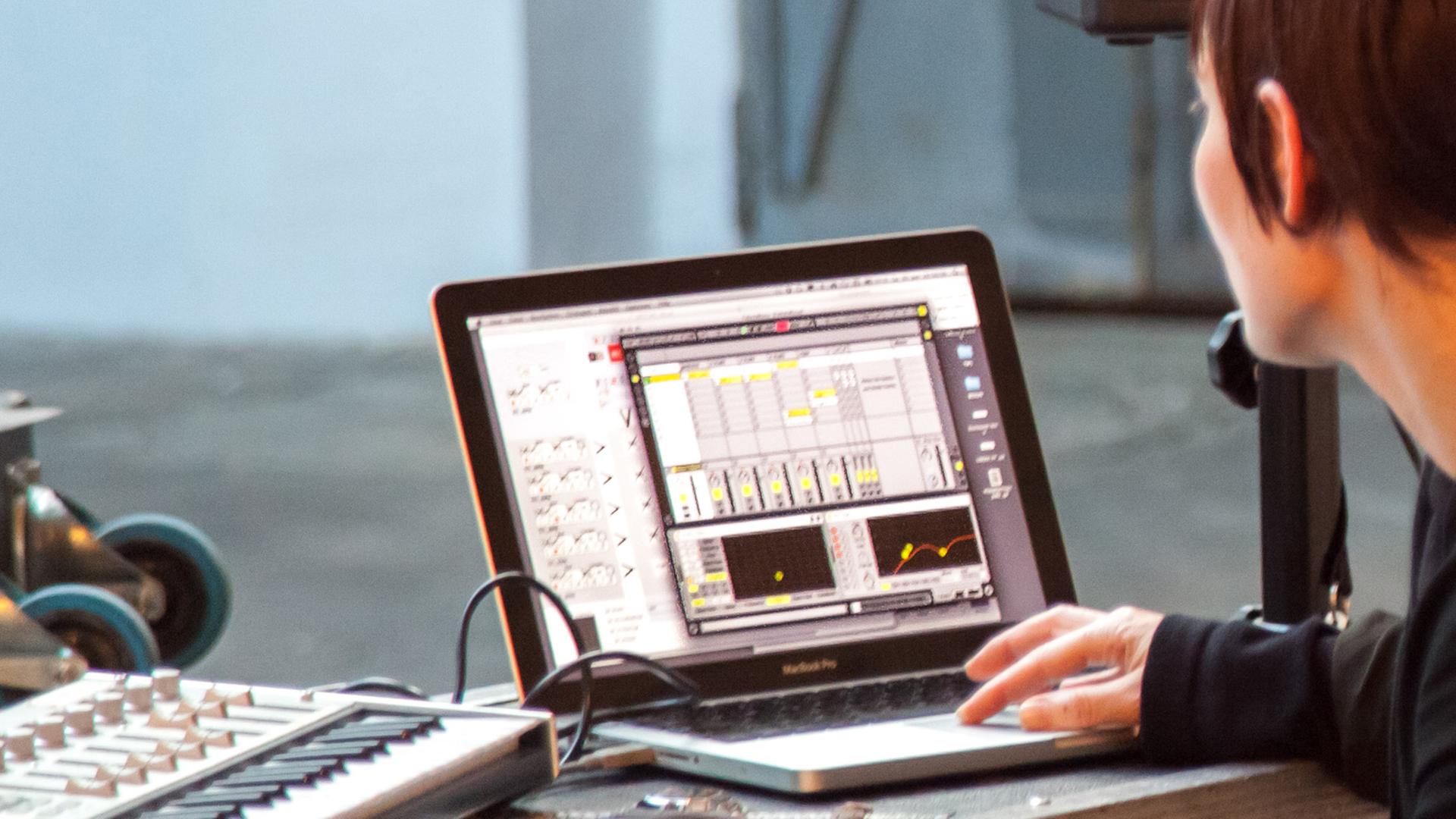 Eine Frau stellt die Sound-Software auf ihrem MacBook-Computer ein. Eine Frau stellt die Sound-Software auf ihrem MacBook-Computer ein.