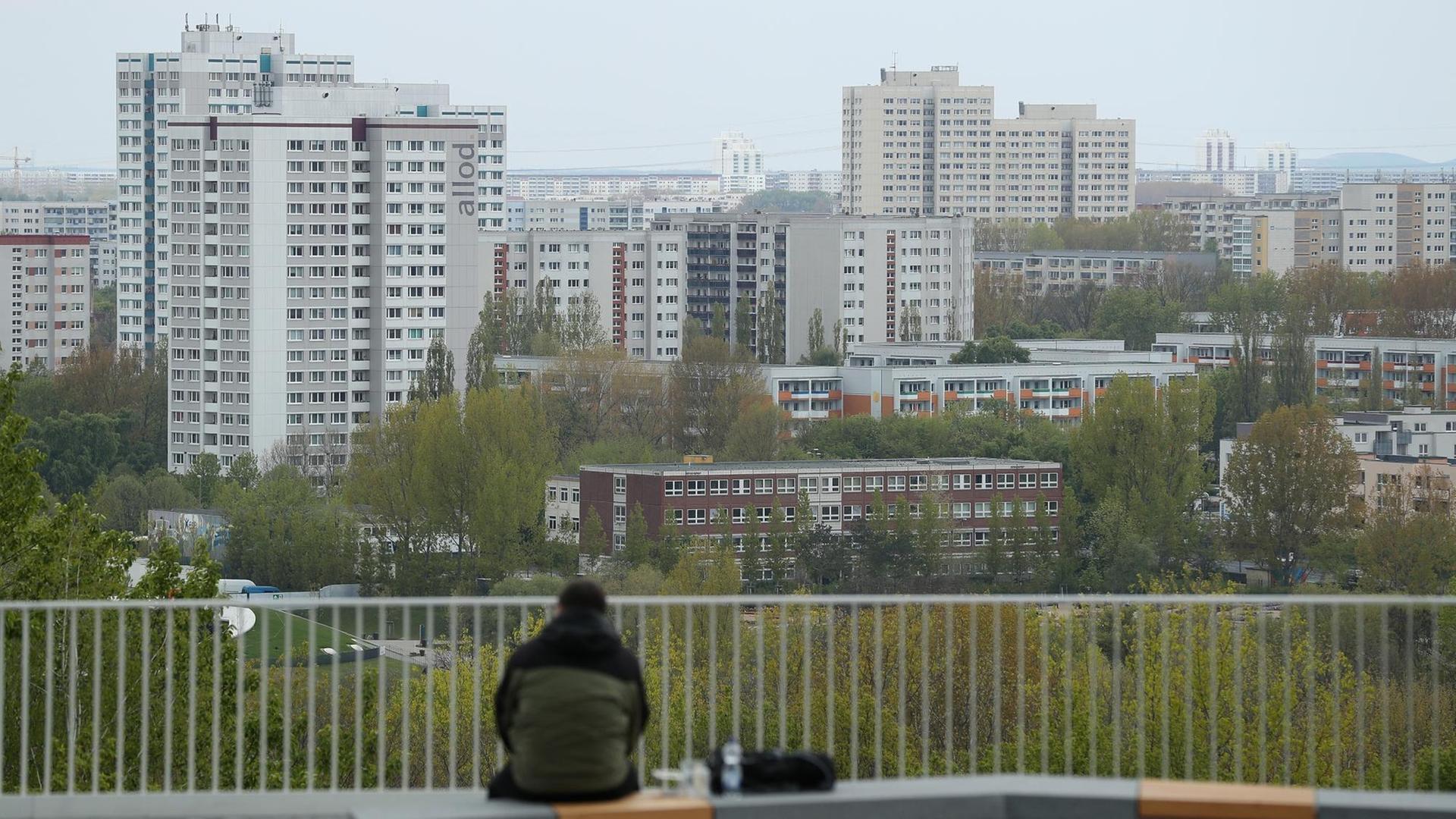 Ein Mann sitzt allein auf einer Terrasse und schaut zu den Plattenbauten von Marzahn hinüber, die zu DDR-Zeiten errichtet wurden. Ein Mann sitzt allein auf einer Terrasse und schaut zu den Plattenbauten von Marzahn hinüber, die zu DDR-Zeiten errichtet wurden.