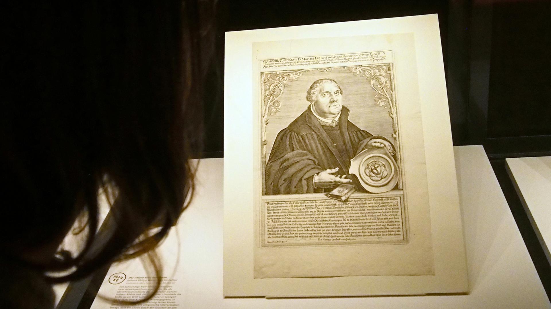 Eine Frau betrachtet in der Herzog August Bibliothek Wolfenbüttel in der Ausstellung "Luthermania - Ansichten einer Kultfigur" ein Porträt von Martin Luther. Eine Frau betrachtet in der Herzog August Bibliothek Wolfenbüttel in der Ausstellung "Luthermania - Ansichten einer Kultfigur" ein Porträt von Martin Luther.