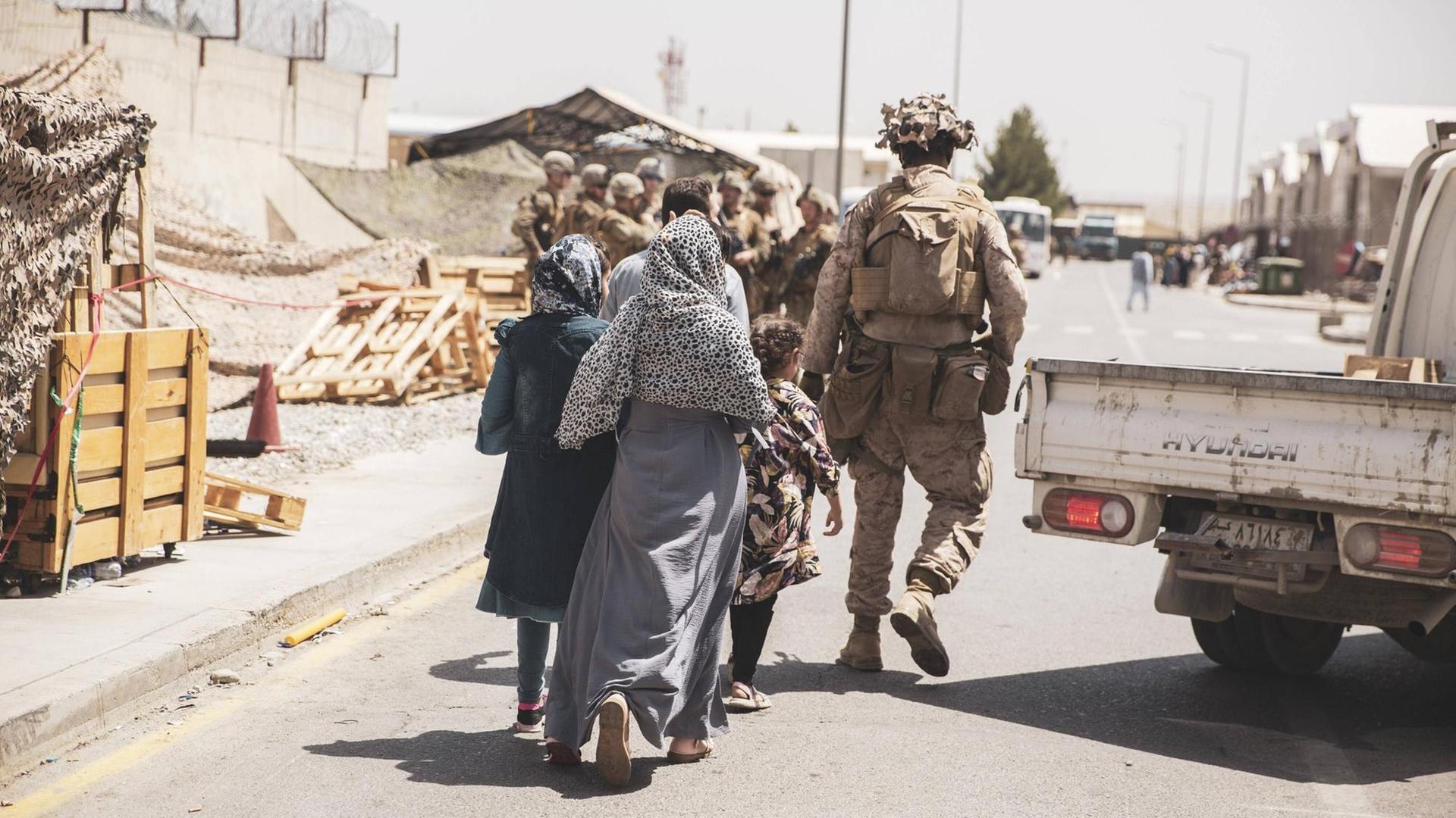 US-Soldaten begleiten eine afghanische Familie am Flughafen Kabul. US-Soldaten begleiten eine afghanische Familie am Flughafen Kabul.