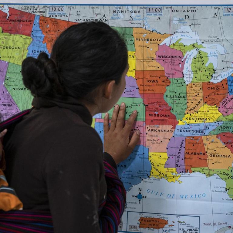 Ein Frau aus Guatemala, die ihr Kind in einem Tragetuch auf dem Rücken trägt, schaut auf eine Karte der USA; Zentrum für Flüchtlinge der Hilfsorganisation Annunciation House