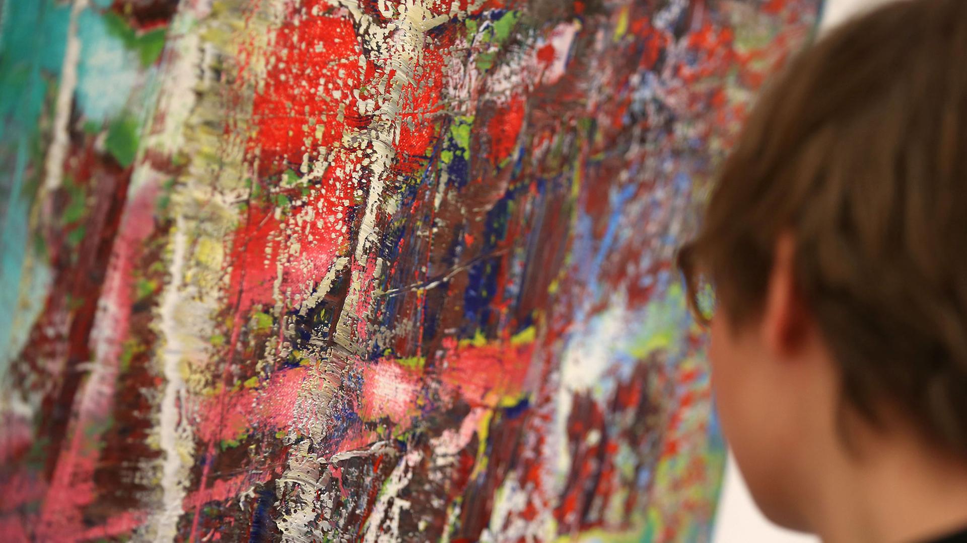 Eine Frau betrachtet ein Gemälde des Malers Gerhard Richter.