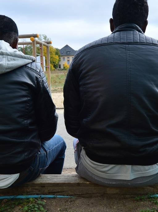 Vier junge Männer aus Eritrea sitzen am 06.10.2015 in Saalfeld in Thüringen vor einer Flüchtlingsunterkunft.