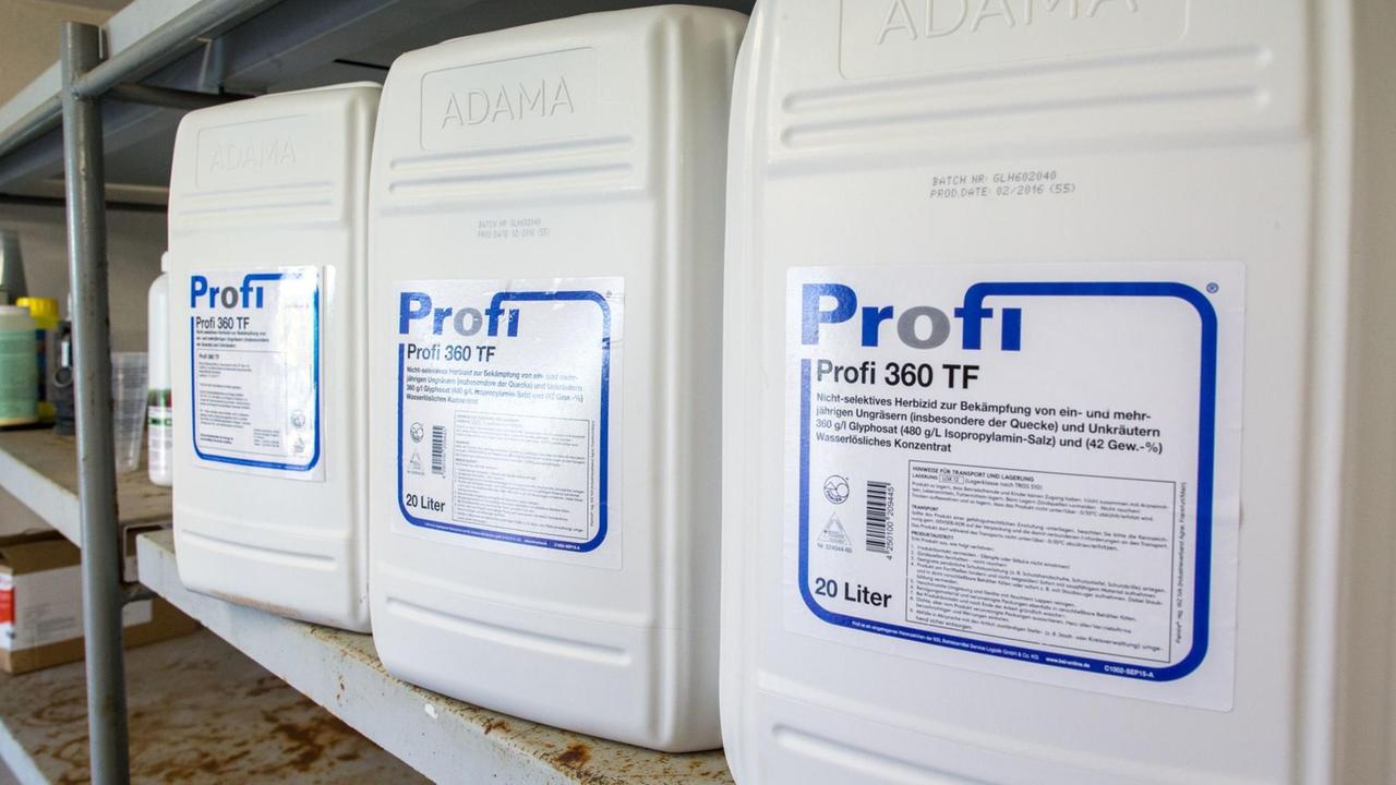 Drei weiße Kanister mit der Aufschrift "Profi 360 TF" und "360 g/l Glyphosat" stehen in einem Metallregal. Drei weiße Kanister mit der Aufschrift "Profi 360 TF" und "360 g/l Glyphosat" stehen in einem Metallregal.
