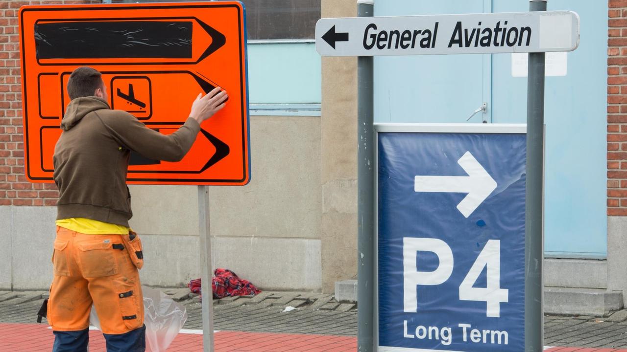 Ein Arbeiter richtet ein Verkehrsschild am Brüsseler Flughafen Zaventem aus.