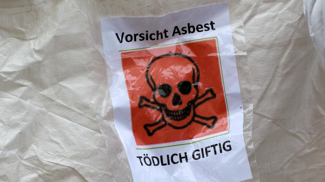 Ein Warnschild mit der Aufschrift "Vorsicht Asbest - Tödlich Giftig" hängt am Freitag (18.11.2011) bei einer Protestaktion der Bürgerinitiative "Stoppt die Deponie Schönberg" vor der Schweriner Staatskanzlei an einem Transportsack. Bürgerinitiativen befürchten Gesundheitsgefährdungen durch die krebsauslösenden Fasern. Ein Warnschild mit der Aufschrift "Vorsicht Asbest - Tödlich Giftig" hängt am Freitag (18.11.2011) bei einer Protestaktion der Bürgerinitiative "Stoppt die Deponie Schönberg" vor der Schweriner Staatskanzlei an einem Transportsack. Bürgerinitiativen befürchten Gesundheitsgefährdungen durch die krebsauslösenden Fasern.