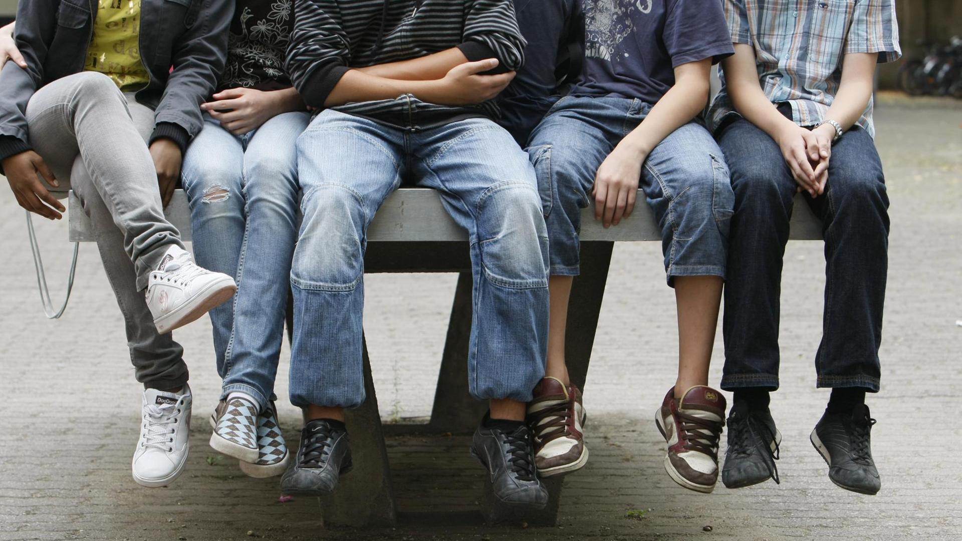 Schüler an einem Gymnasium sitzen nebeneinander auf einer Tischtennis-Platte. Schüler an einem Gymnasium sitzen nebeneinander auf einer Tischtennis-Platte.