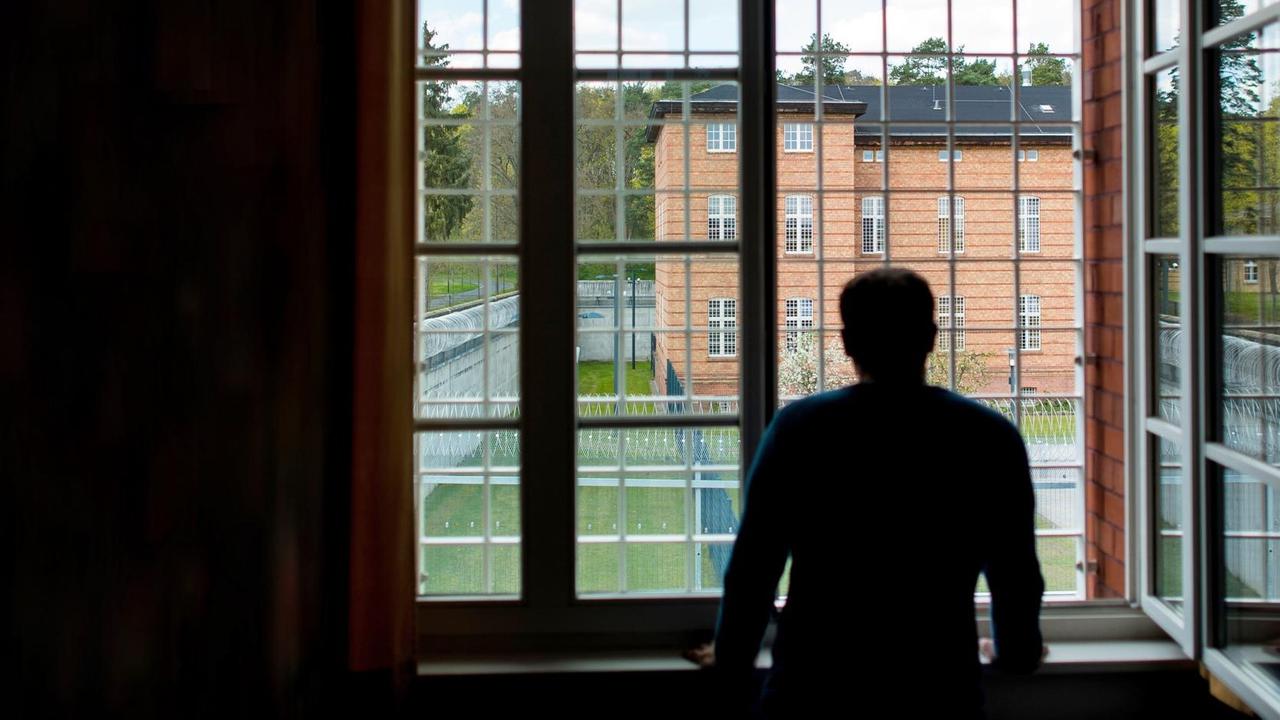 Die Silhouette eines Mannes vor einem vergitterten Fenster. Die Silhouette eines Mannes vor einem vergitterten Fenster.