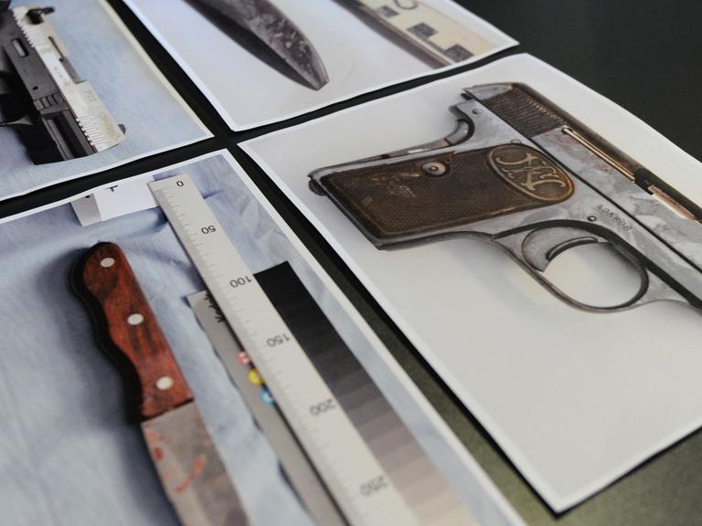 Auf einem Tisch liegen Fotos von zwei Pistolen und zwei Messern.
