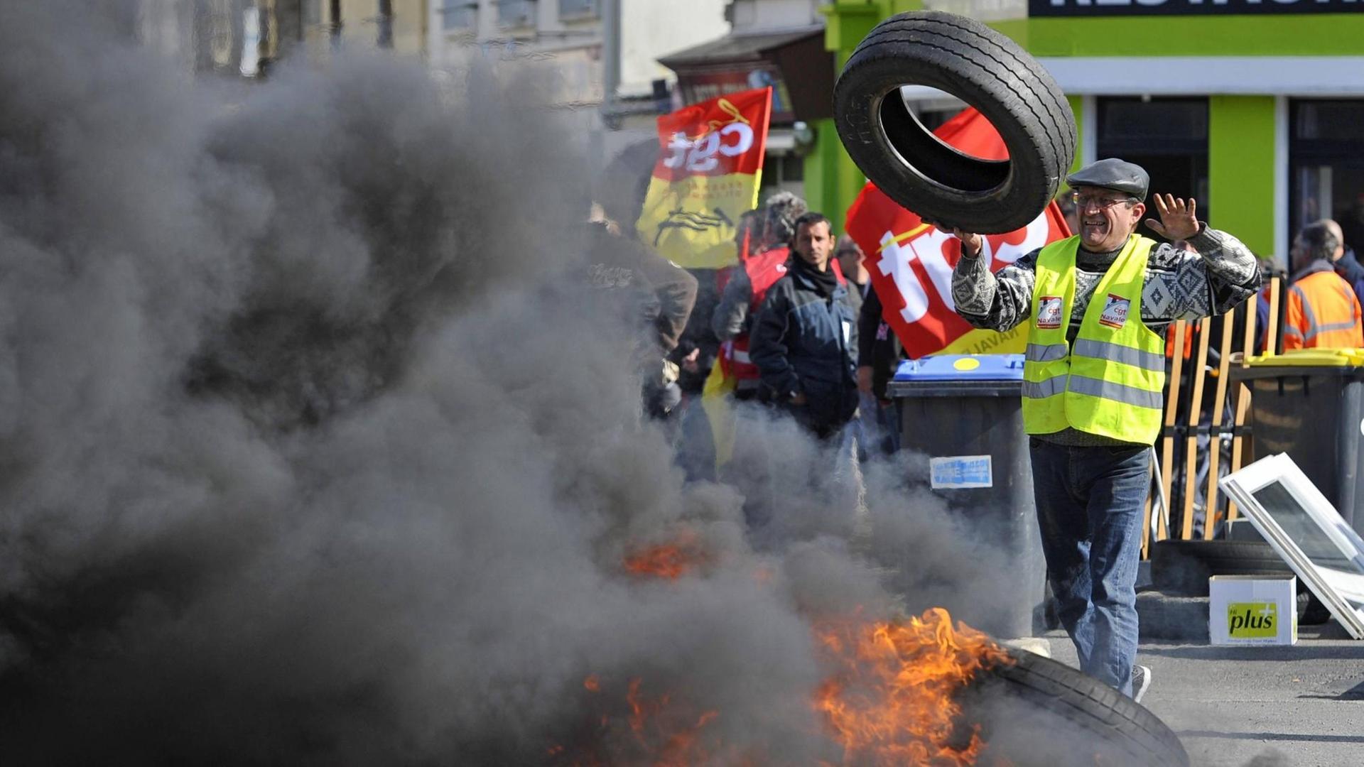 Streikende haben die Zufahrt zu einer Straße mit brennenden Autoreifen blockiert, um gegen die Arbeitsmarkt-Reform der französischen Regierung zu protestieren. Streikende haben die Zufahrt zu einer Straße mit brennenden Autoreifen blockiert, um gegen die Arbeitsmarkt-Reform der französischen Regierung zu protestieren.