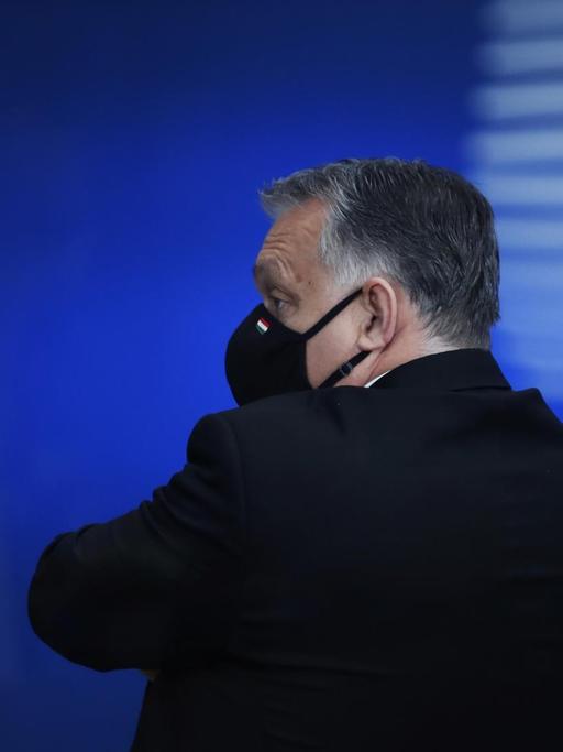 Ungarns Premier Viktor Orbán nach einem EU-Gipfel im Dezember 2020; er steht alleine mit Gesichtsmaske und wendet sich von der Kamera ab