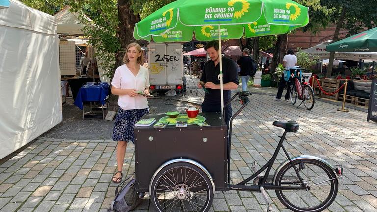 Eine junge Frau verteilt vor einem Wahlstand Flyer. Eine junge Frau verteilt vor einem Wahlstand Flyer.