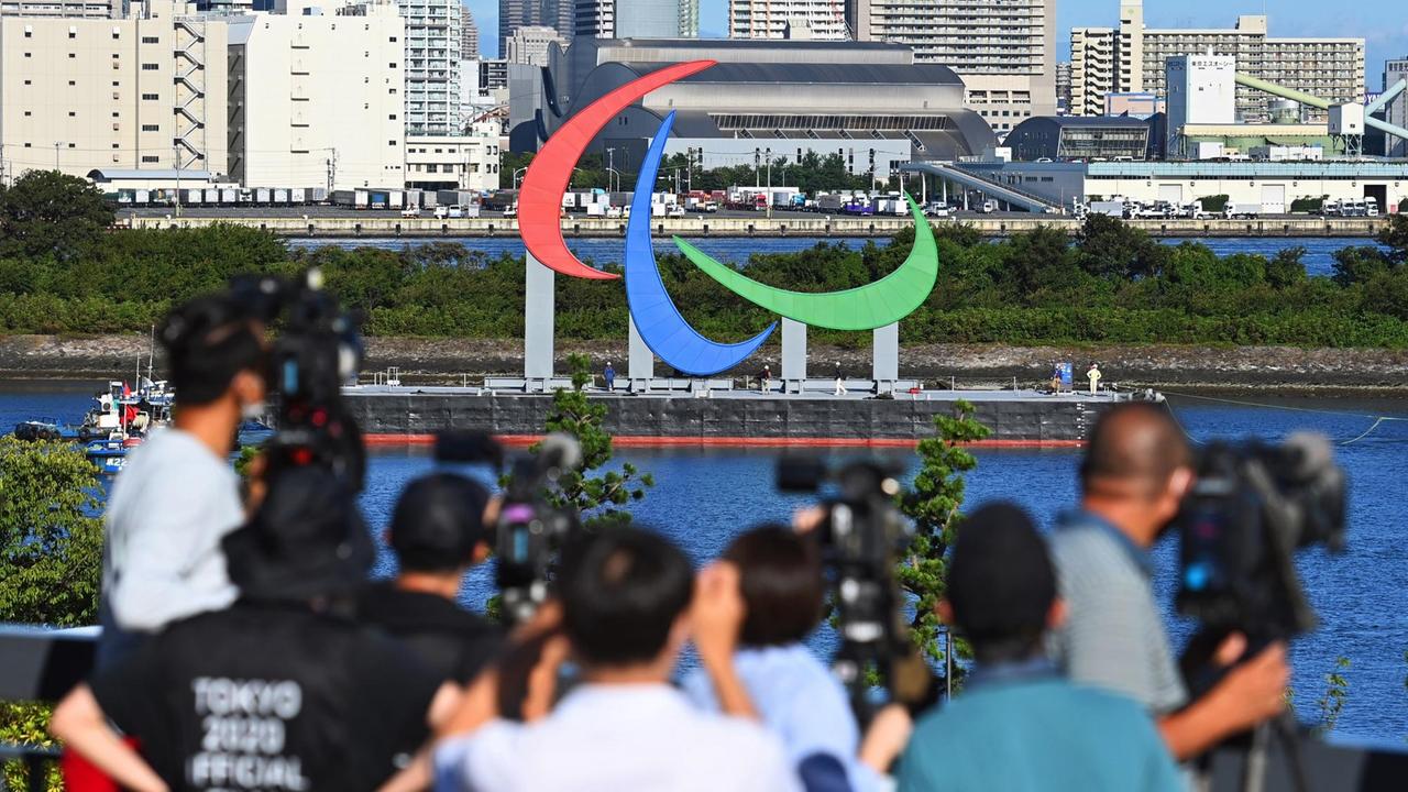 Fernsehkameras zeichnen die Installation des Symbols der Paraplympics auf dem See eines Parks in Tokio auf. Fernsehkameras zeichnen die Installation des Symbols der Paraplympics auf dem See eines Parks in Tokio auf.