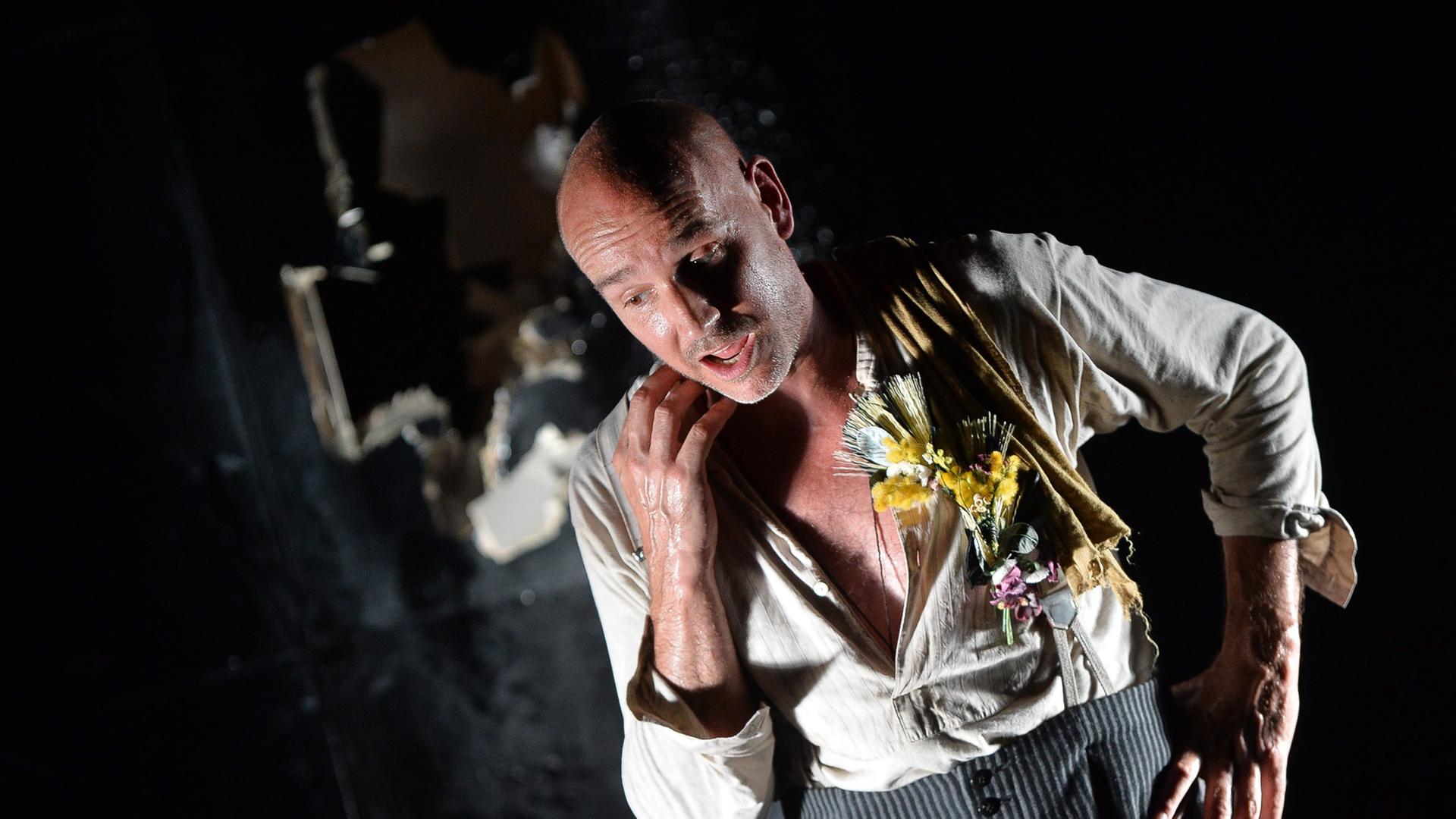 Paul Herwig als Georg Trakl in "Der Abschied", Schauspieler mit Glatze, hellem aufgerissenen Hemd und grauer Hose auf einer dunklen Bühne Paul Herwig als Georg Trakl in "Der Abschied", Schauspieler mit Glatze, hellem aufgerissenen Hemd und grauer Hose auf einer dunklen Bühne