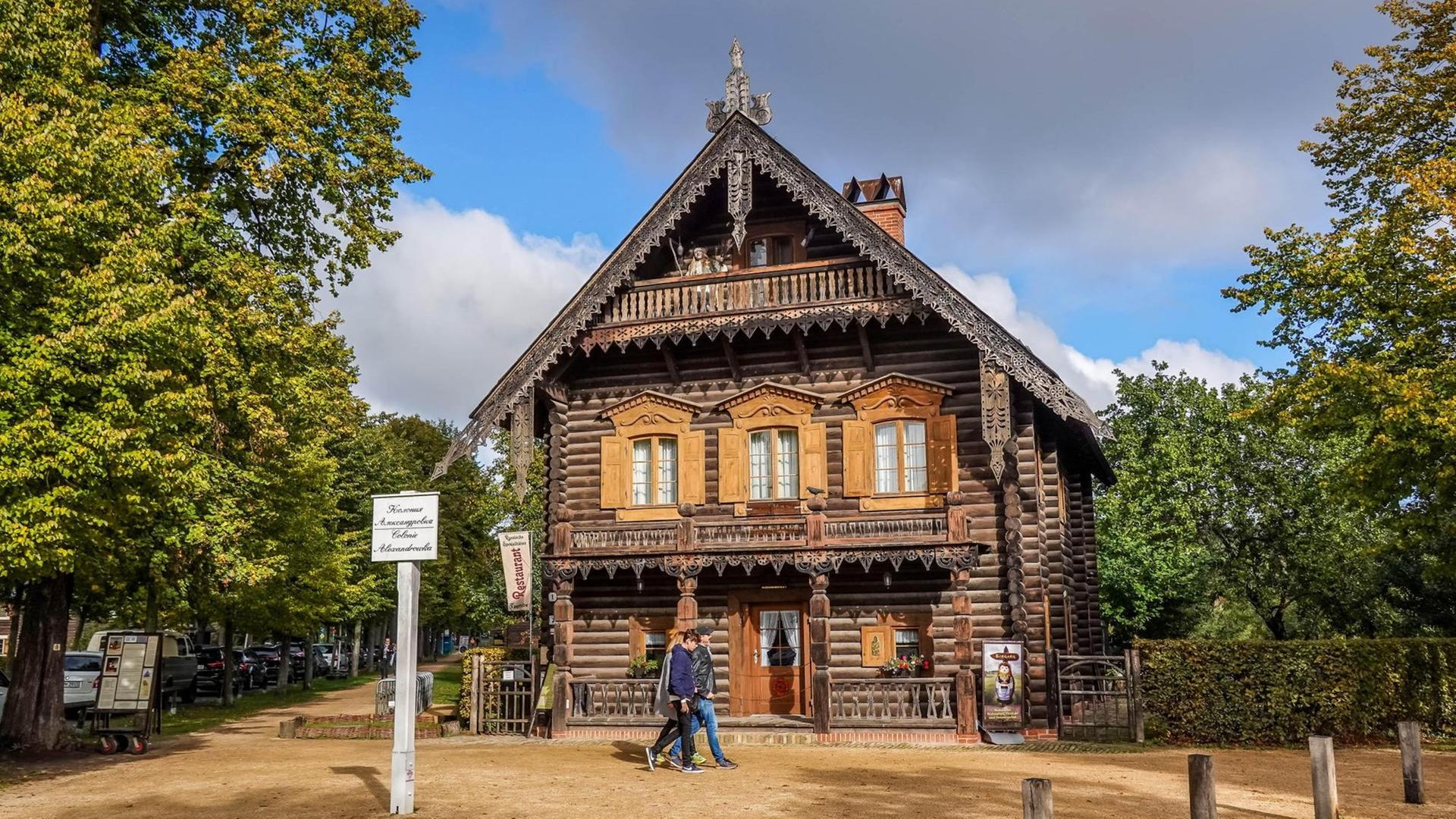 Ein Holzhaus in der Russischen Kolonie Alexandrowka in Potsdam. Davor sind zwei Spaziergänger. Ein Holzhaus in der Russischen Kolonie Alexandrowka in Potsdam. Davor sind zwei Spaziergänger.