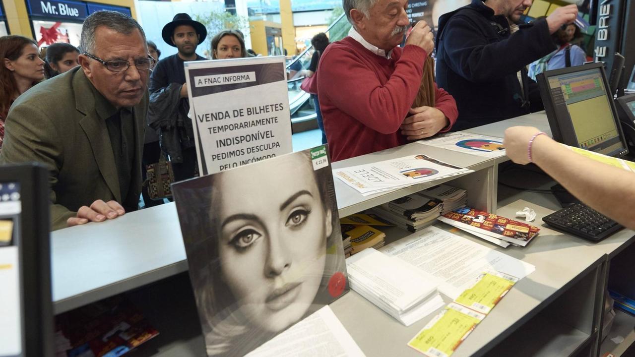 Fans der Sängerin Adele stehen an einem Ticket-Schalter, um Karten für ein Konzert zu kaufen. Fans der Sängerin Adele stehen an einem Ticket-Schalter, um Karten für ein Konzert zu kaufen.