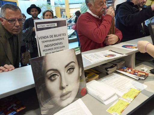 Fans der Sängerin Adele stehen an einem Ticket-Schalter, um Karten für ein Konzert zu kaufen.