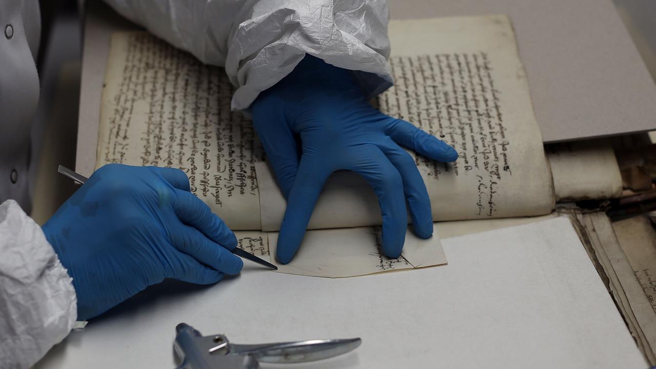 Eine Restauratorin reinigt im Restaurierungszentrum des Kölner Stadtarchivs eine historische Schrift. Eine Restauratorin reinigt im Restaurierungszentrum des Kölner Stadtarchivs eine historische Schrift.