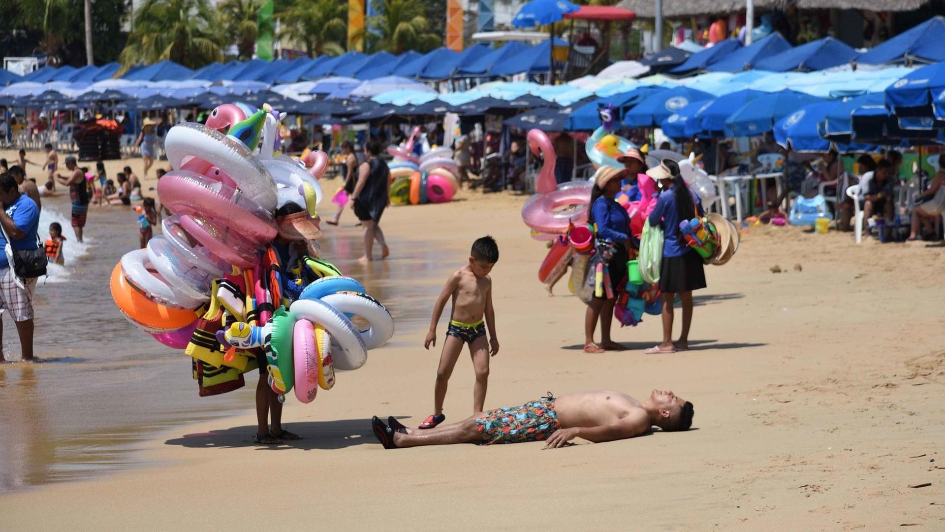 Strandszene in Acapulco mit Badegästen, Sonnenschirmen und Badetierverkäufern. Strandszene in Acapulco mit Badegästen, Sonnenschirmen und Badetierverkäufern.