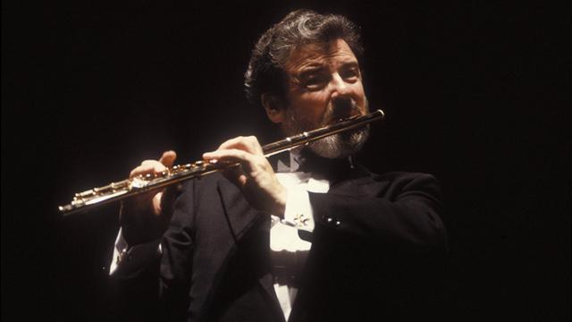 Der Flötist James Galway spielt auf seiner goldenen Flöte, er trägt einen Konzert-Frack mit weißem Hemd