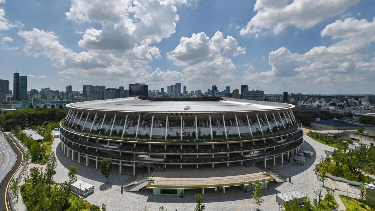 Fotografie des neu gebauten Japan National Stadium mit der Stadtsilhouette von Tokio im Hintergrund. Fotografie des neu gebauten Japan National Stadium mit der Stadtsilhouette von Tokio im Hintergrund.
