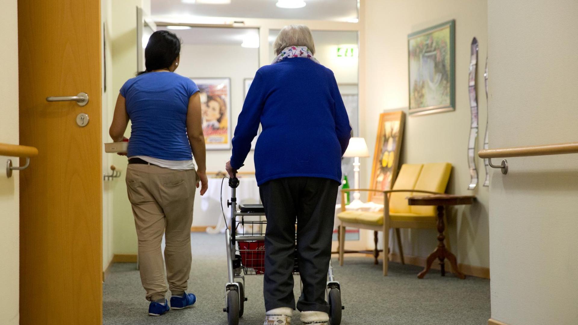 Eine Pflegerinn begleitet am 12.02.2015 in Hamburg eine Bewohnerin eines Seniorenwohnheims mit ihrer Gehhilfe (Rollator). Eine Pflegerinn begleitet am 12.02.2015 in Hamburg eine Bewohnerin eines Seniorenwohnheims mit ihrer Gehhilfe (Rollator).