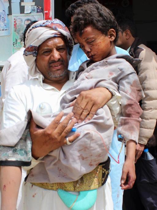 Ein Mann trägt ein verletztes Kind in ein Krankenhaus