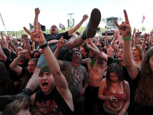 Besucher eines Konzertes beim Woodstock Bus Stop Festival in Kostryzyn on Odra in Polen recken die Hände zum Metal Sign geformt in die Höhe.