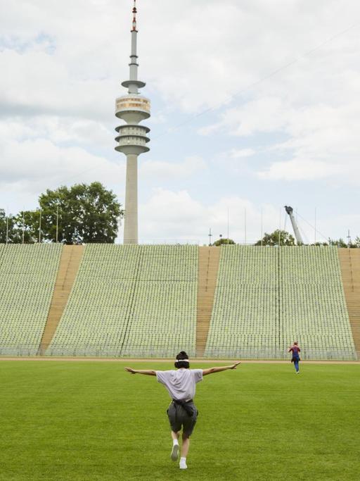 Performer im Münchner Olympiastadion bei der Abschiedsgala für Matthias Lilienthal, im Hintergrund der Olympiaturm.