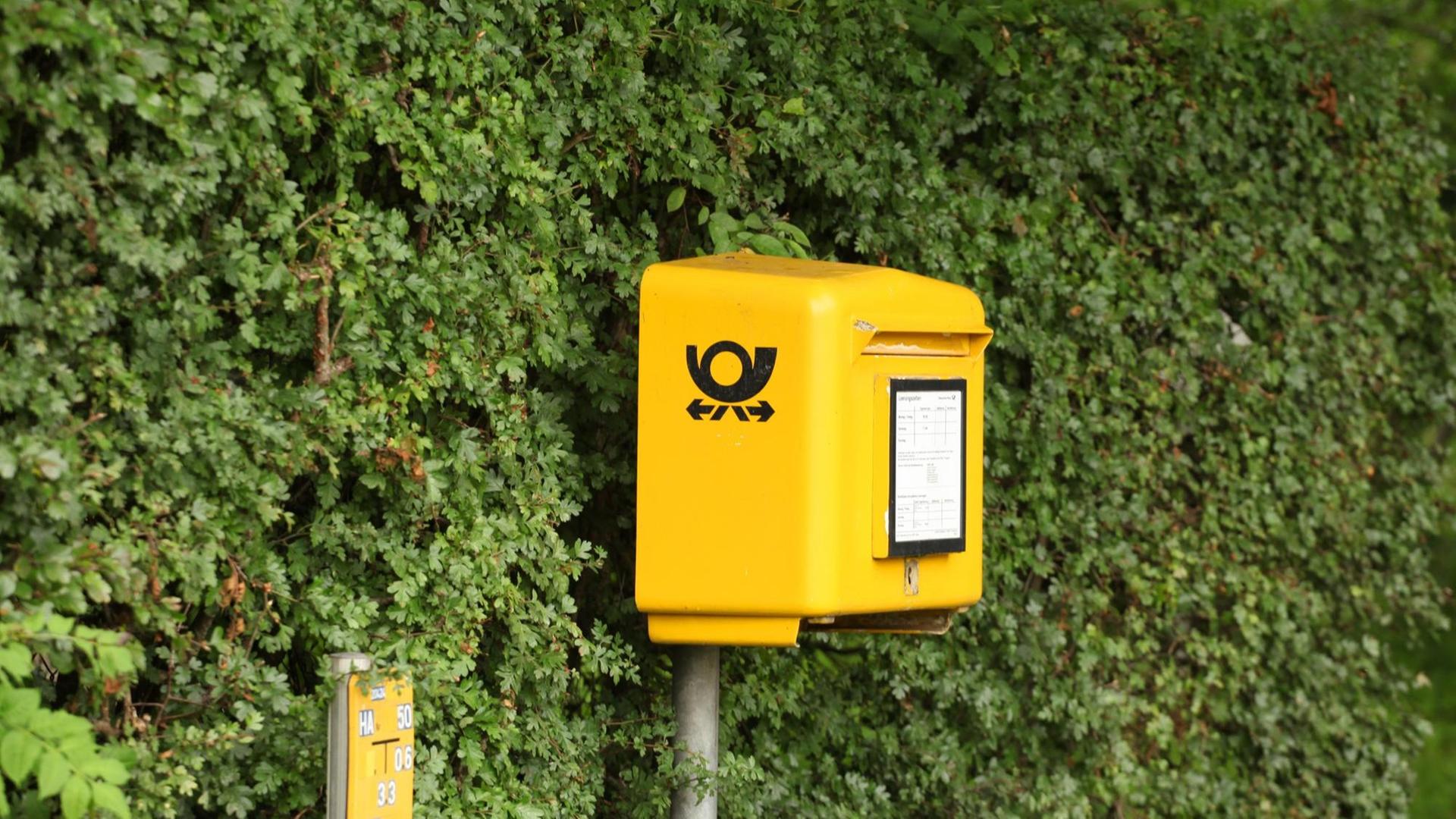 Ein Postkasten der Deutschen Post steht in Timmendorfer Strand vor einer grünen Hecke. Ein Postkasten der Deutschen Post steht in Timmendorfer Strand vor einer grünen Hecke.