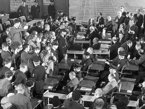 Der erste AuschwitzProzess wird am 20.12.1963 im Plenarsaal der Frankfurter Stadtverordnetenversammlung eröffnet. Das Bild zeigt einen Blick auf die Pressefotografen und Kameraleute, die die Angeklagten aufnehmen. Die Angeklagten sitzen flankiert von Poli