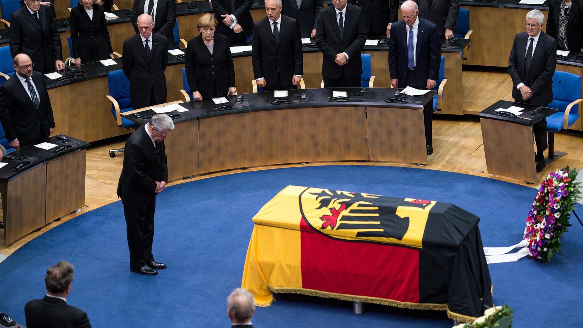 Bundespräsident Gauck verneigt sich vor dem mit einer Deutschlandflagge bedeckten Sarg von Hans-Dietrich Genscher im Alten Plenarsaal in Bonn. Bundespräsident Gauck verneigt sich vor dem mit einer Deutschlandflagge bedeckten Sarg von Hans-Dietrich Genscher im Alten Plenarsaal in Bonn.