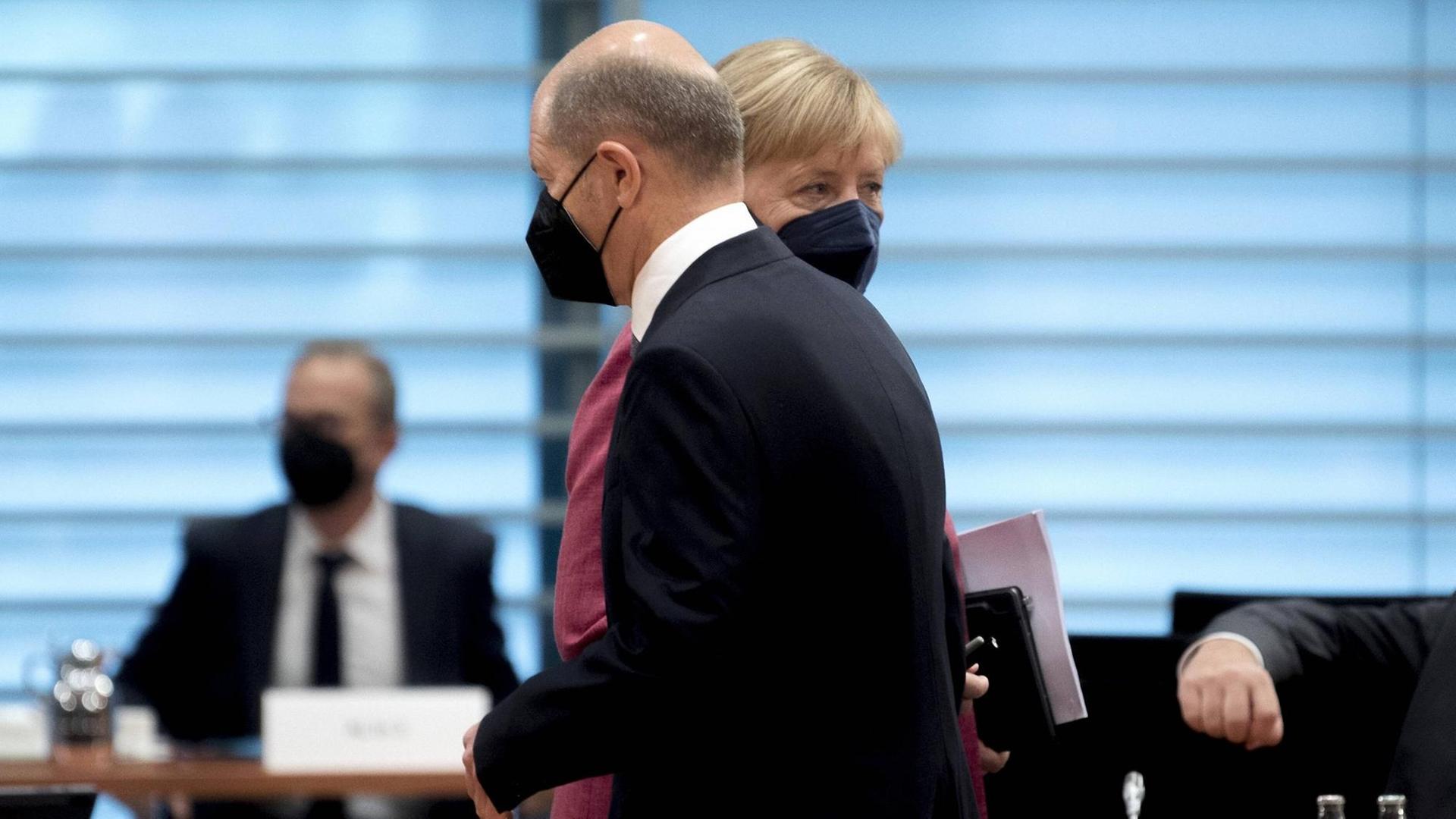 Olaf Scholz (SPD) geht in einer Kabinettsitzung an Bundeskanzlerin Angela Merkel (CDU) vorbei. Olaf Scholz (SPD) geht in einer Kabinettsitzung an Bundeskanzlerin Angela Merkel (CDU) vorbei.