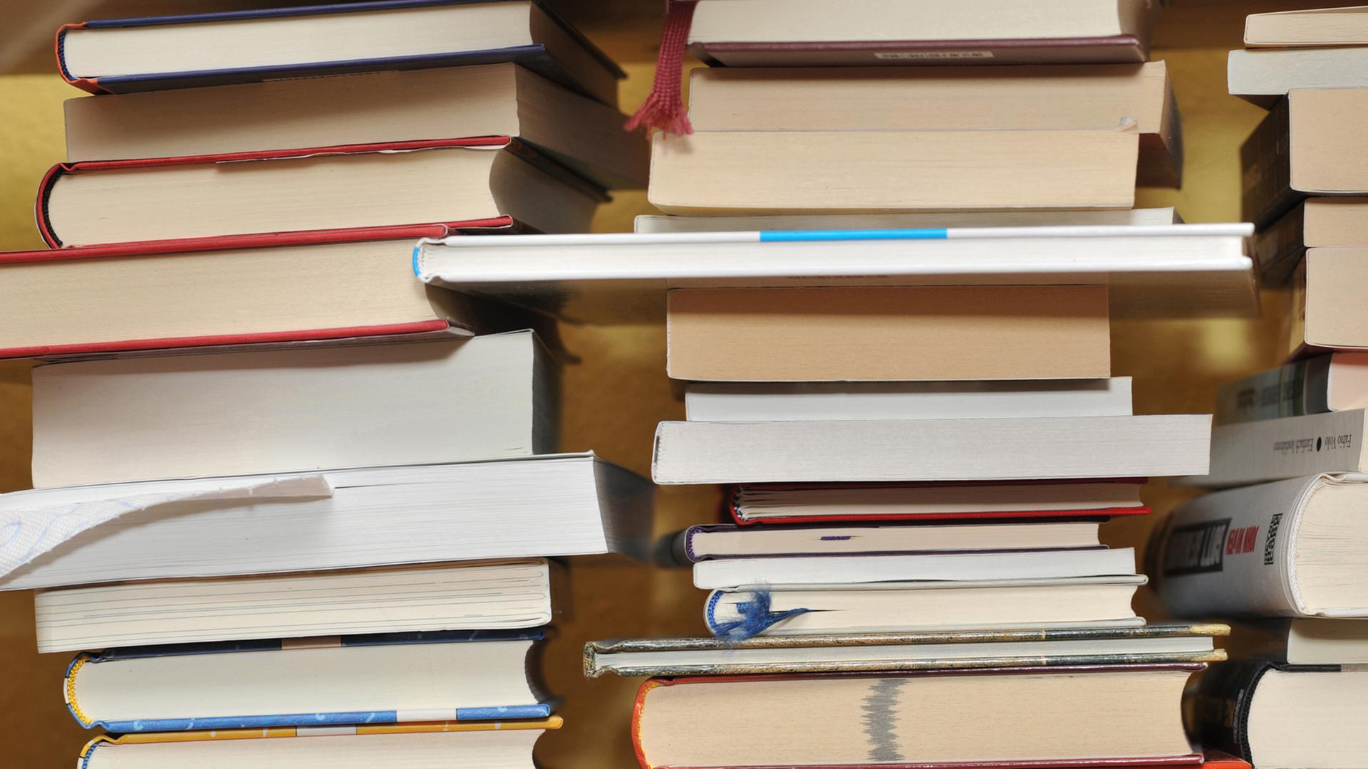 Mehrere Bücher liegen auf drei Stapeln nebeneinander. Mehrere Bücher liegen auf drei Stapeln nebeneinander.
