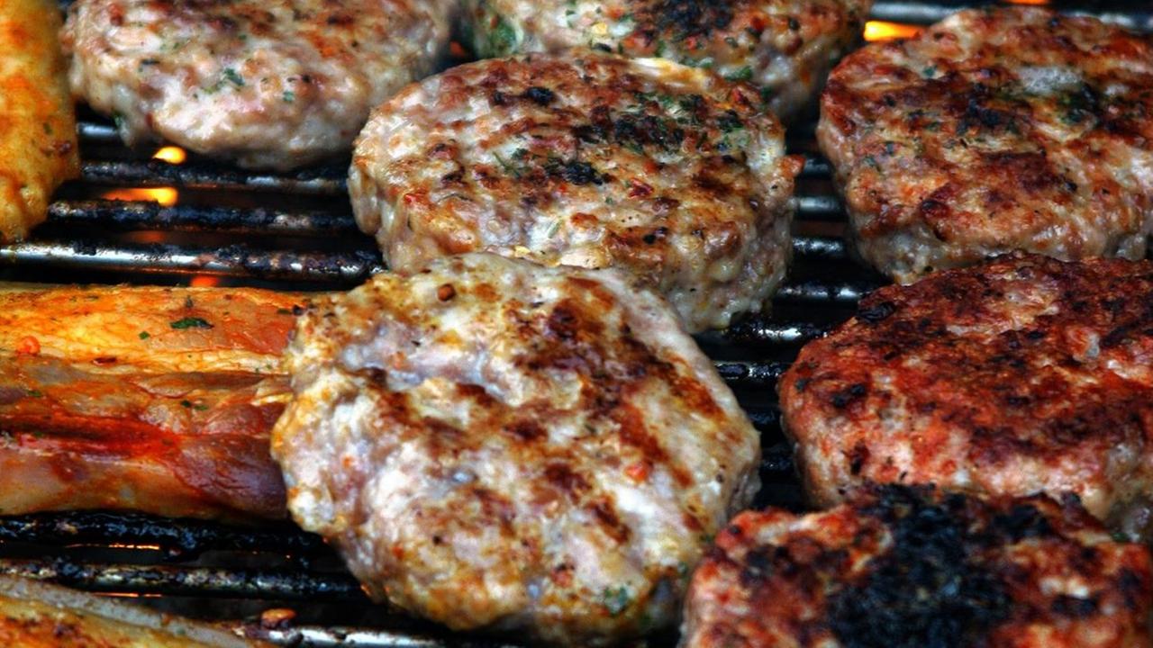 Frikadellen und Bauchfleisch liegen auf einem Grillrost. Frikadellen und Bauchfleisch liegen auf einem Grillrost.