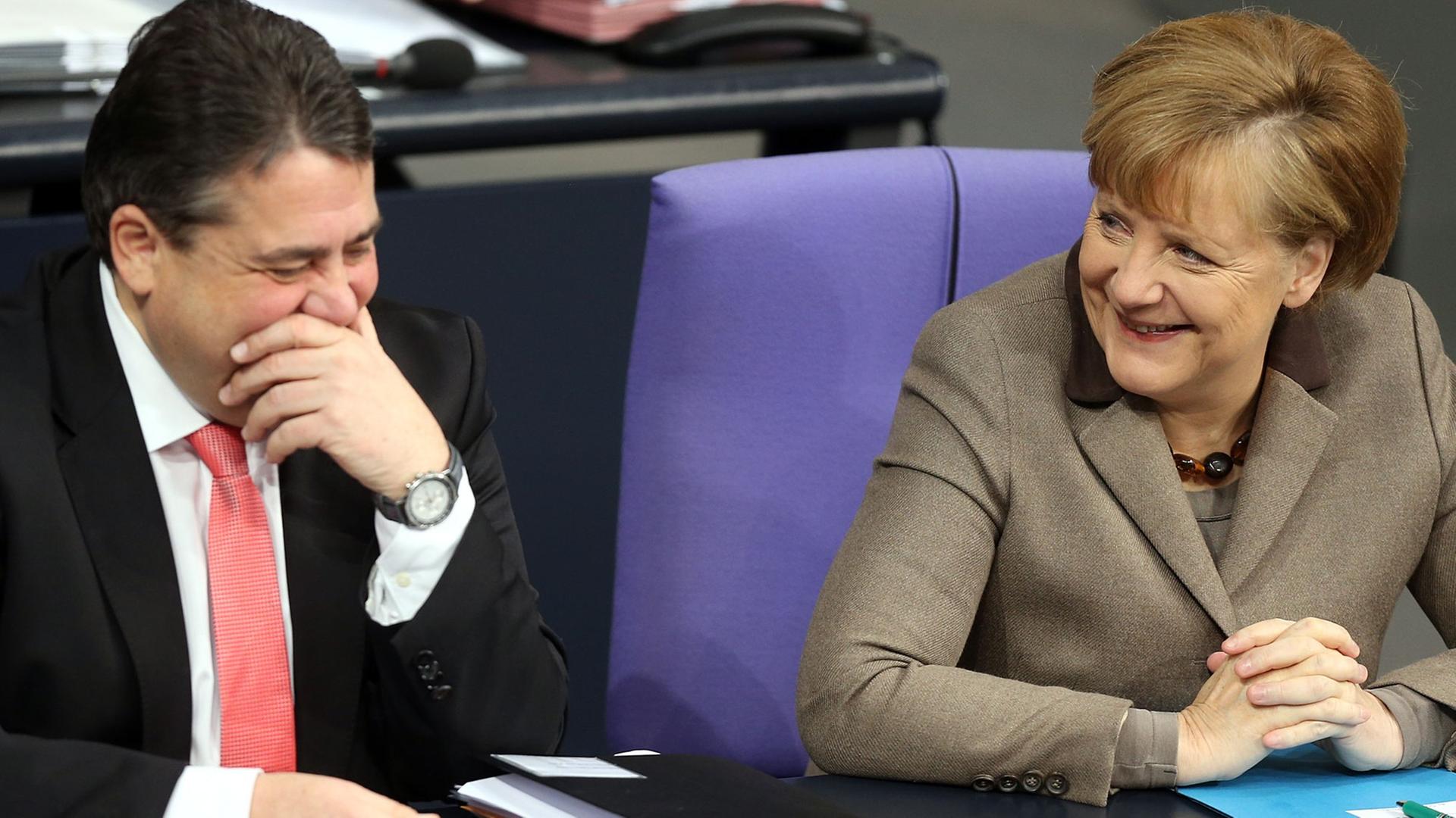 Bundeswirtschaftsminister Sigmar Gabriel (SPD) und Bundeskanzlerin Angela Merkel (CDU) lachen auf ihren Sitzen während einer Debatte im Bundestag. Bundeswirtschaftsminister Sigmar Gabriel (SPD) und Bundeskanzlerin Angela Merkel (CDU) lachen auf ihren Sitzen während einer Debatte im Bundestag.