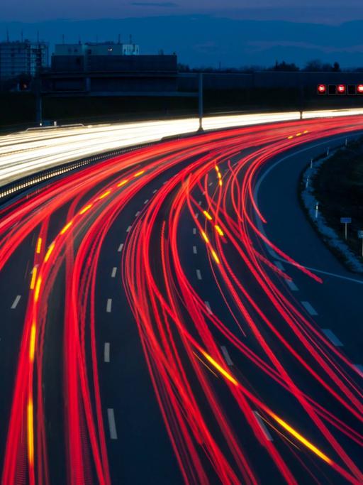 Unzählige Autos fahren bei Nacht auf einer Autobahn und erzeugen rote und gelbe Lichtspuren.
